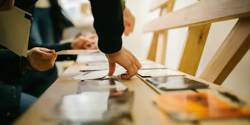 Hand picking up postcard from table. 