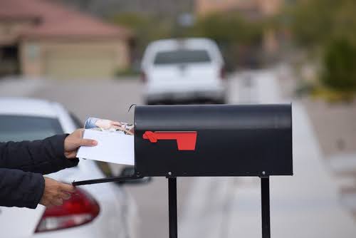 Person putting a letter in a mailbox.